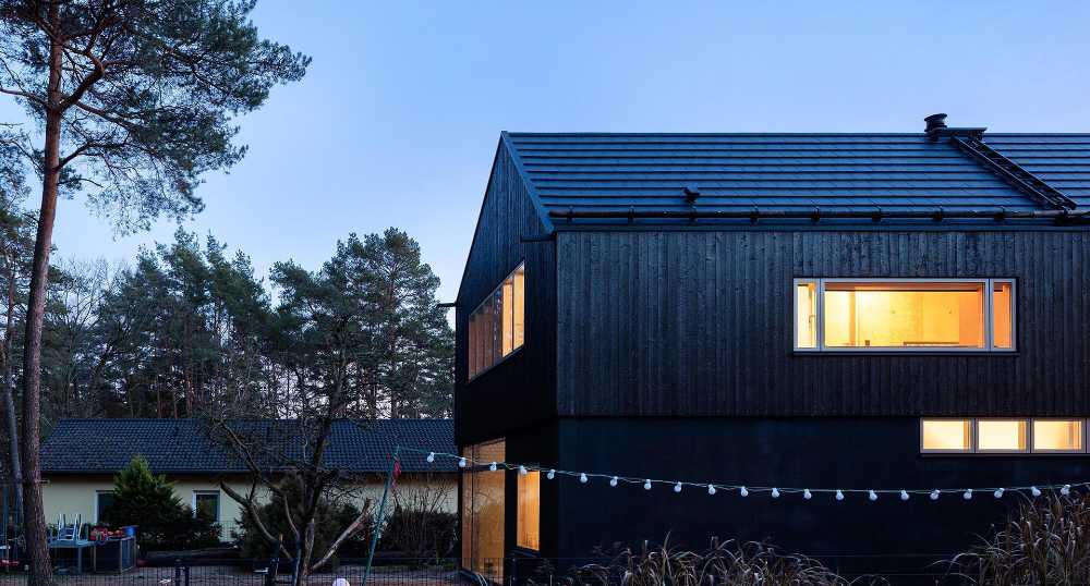 Vivienda de madera en tonos oscuros. Superficies brillantes de color negro intenso a tonos plateados y azulados