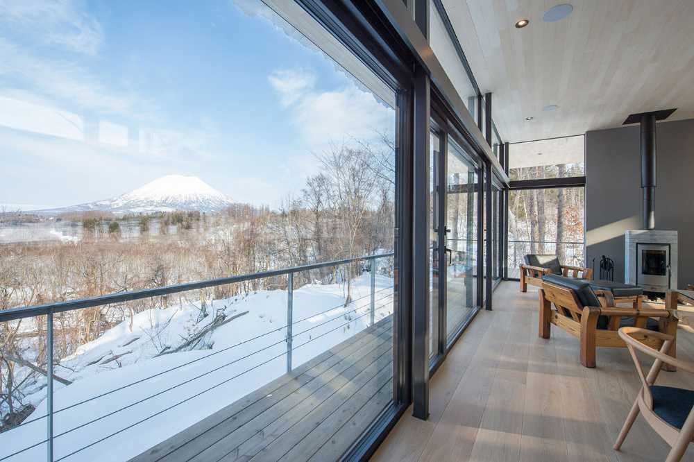Architectural dialogue between cedar and metal for the Hiyoku house, set against the backdrop of the snow-capped mountains of Japan.