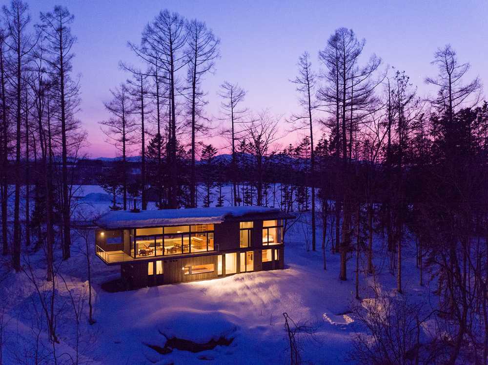 Architectural dialogue between cedar and metal for the Hiyoku house, set against the backdrop of the snow-capped mountains of Japan.