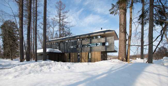 Architectural dialogue between cedar and metal for the Hiyoku house, set against the backdrop of the snow-capped mountains of Japan.
