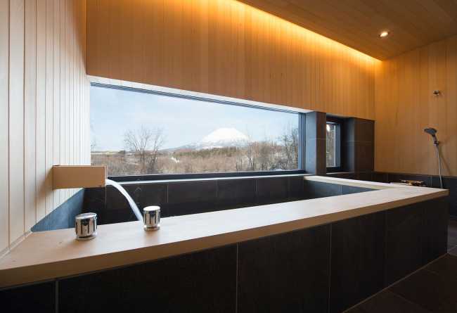 Architectural dialogue between cedar and metal for the Hiyoku house, set against the backdrop of the snow-capped mountains of Japan.