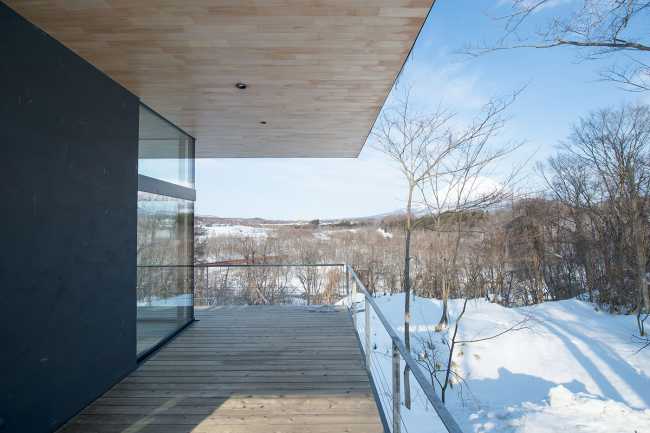 Architectural dialogue between cedar and metal for the Hiyoku house, set against the backdrop of the snow-capped mountains of Japan.