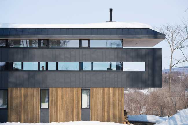 Architectural dialogue between cedar and metal for the Hiyoku house, set against the backdrop of the snow-capped mountains of Japan.
