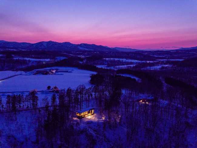 Architectural dialogue between cedar and metal for the Hiyoku house, set against the backdrop of the snow-capped mountains of Japan.