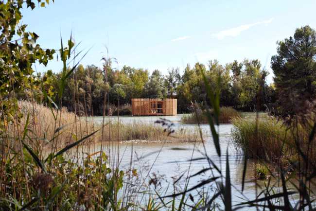 Wooden suites at the Grand Cepage Hotel, resembling the sophisticated nests among the reeds, are reflected in the lake for a primordial living experience