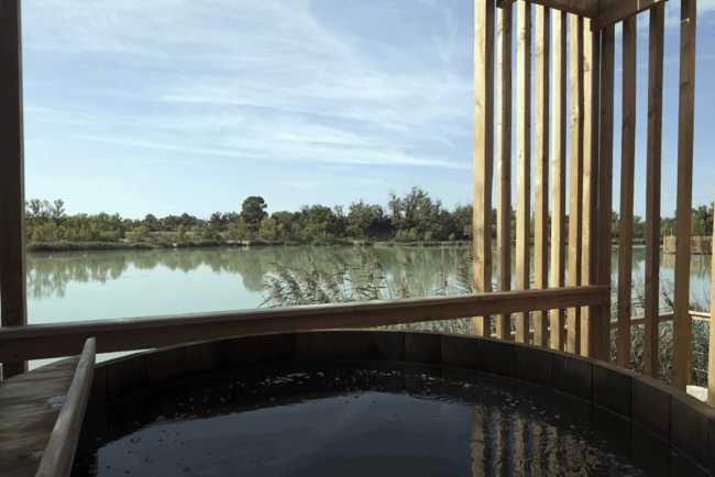 Wooden suites at the Grand Cepage Hotel, resembling the sophisticated nests among the reeds, are reflected in the lake for a primordial living experience