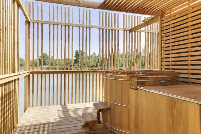 Wooden suites at the Grand Cepage Hotel, resembling the sophisticated nests among the reeds, are reflected in the lake for a primordial living experience