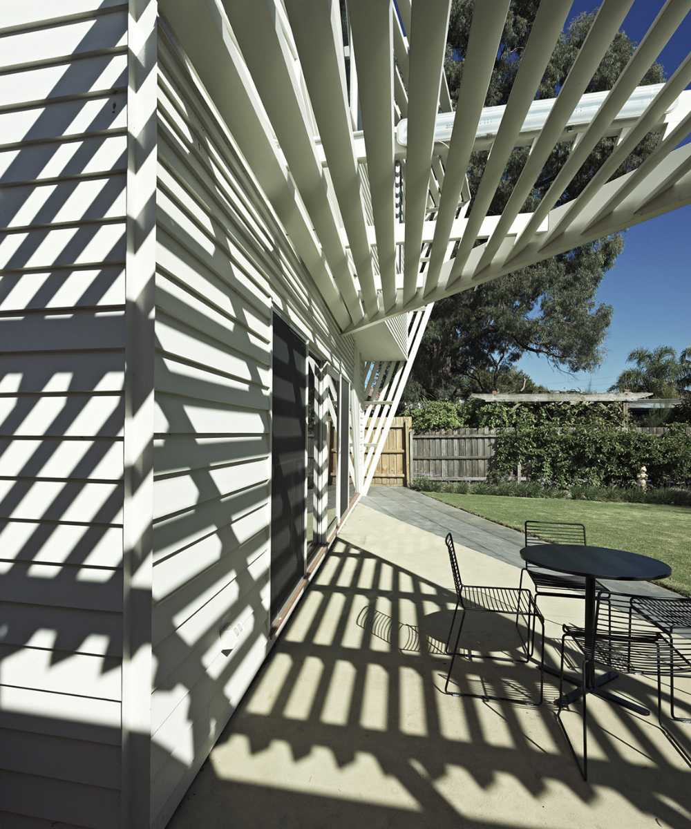 Wooden house with play of light and shadow on the terrace