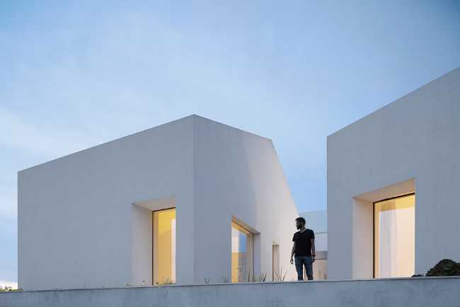 Old renovated farmhouse. Three white volumes stand on a rustic ground floor